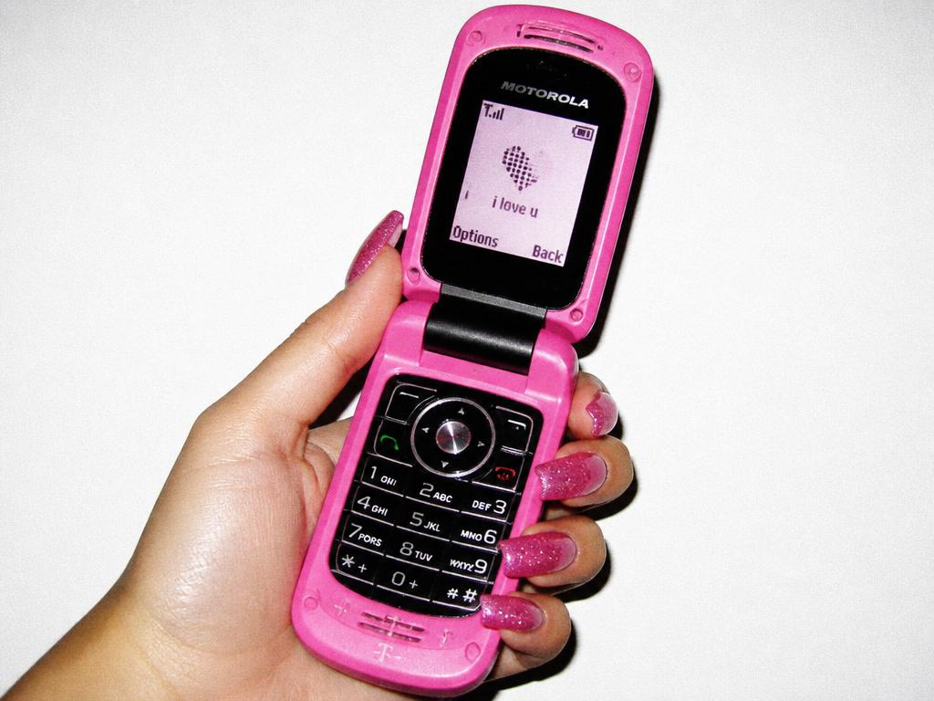 Hand holding a pink flip phone